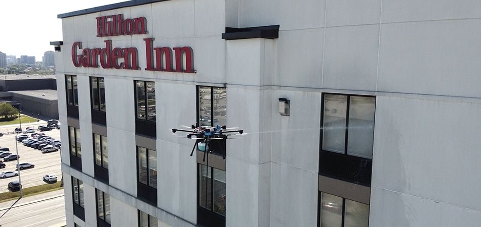 Dron limpiando la fachada y el rótulo de un hotel en funcionamiento
