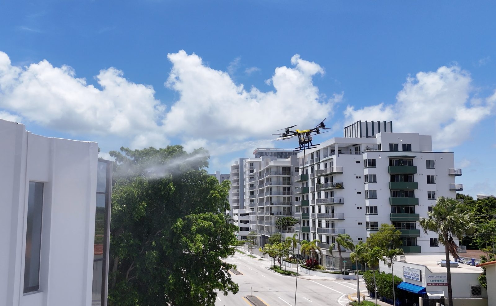 Dron de EURODRON limpiando la fachada de una torre residencial mientras el equipo opera desde tierra